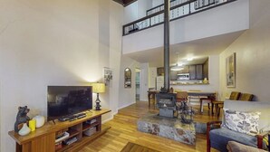 Ein großzügiger Wohnbereich mit Fernseher, Holz-Entertainment-Möbel und Kamin.