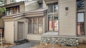Ein modernes, zweistöckiges Haus mit Natursteinfassade, einer Garage und einer Veranda.