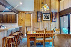 A wooden interior with a dining table, bar stools, and framed pictures on the wall. - Skier's paradise with mountain views, pool, hot tub & game room - dog-friendly (Mammoth Lakes)