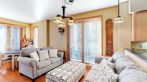 A living room with a sofa, ottoman, and a dining table with chairs. - Convenient mountain getaway with views & on-site golf - near skiing (Mammoth Lakes)