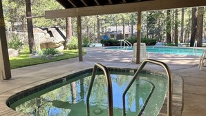 A swimming pool with a covered area, surrounded by trees and a grassy area. - Modern condo with WiFi, fireplace, pool, & hot tub - near local attractions (Mammoth Lakes)