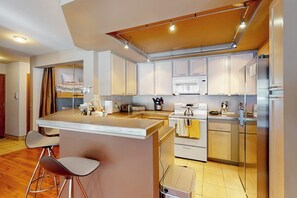 A modern kitchen with a central island, bar stools, a microwave, and a stove. - Updated townhome with a fireplace, grill, pool, hot tub - easy access to slopes (Mammoth Lakes)