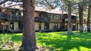 Un immeuble de deux étages doté de balcons, d’une cour verdoyante et de grands arbres.