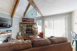 Ein Wohnzimmer mit Kamin aus Stein, einem Fernseher und einem Sofa.