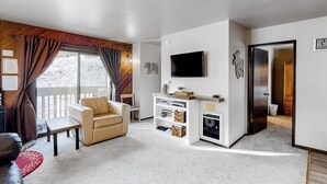 A living room with a sofa, a television, and a fireplace. - Charming mountain condo w/ mountain views, shared pool & hot tub (Mammoth Lakes)