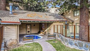 A pool area with a stone wall, a wooden deck, and a bench. - Charming mountain condo w/ mountain views, shared pool & hot tub (Mammoth Lakes)