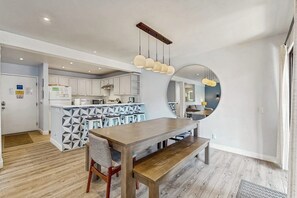 Eine moderne Küche mit weißen Schränken, einer zentralen Kochinsel und einem Essbereich mit Holztisch und Bank.