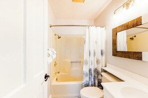 Et badeværelse med badekar, toilet og et spejl.