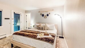 A bedroom with a bed, bedside table, lamp, and wall decorations. - Marvelous & elegant two-story condo w/mtn views, private hot tub, gas fireplace (Mammoth Lakes)