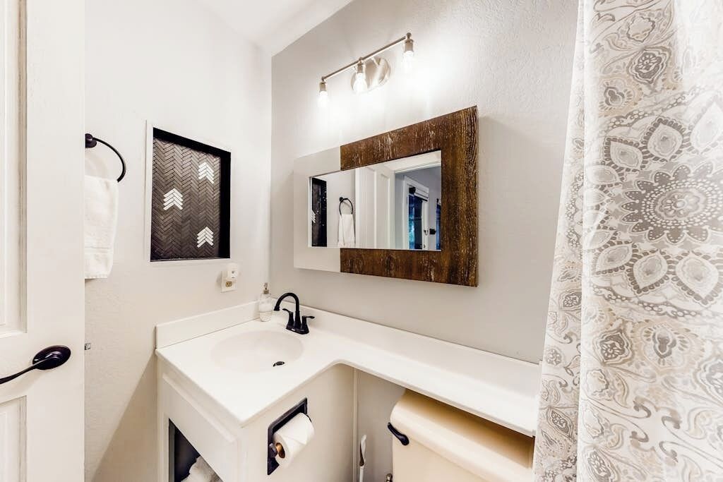 Een badkamer met een witte wasbak, een spiegel, een handdoekhouder en een douchegordijn.