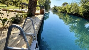 A wooden deck with a metal ladder leading to a calm water body, surrounded by greenery. - La Villa sur la Sorgue: Waterfront and Downtown in L'Isle-sur-la-Sorgue (L'Isle-sur-la-Sorgue)