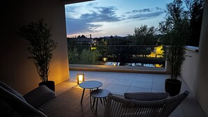 A balcony with a view of a body of water, two potted plants, a small round table, and two chairs. - La Villa sur la Sorgue: Waterfront and Downtown in L'Isle-sur-la-Sorgue (L'Isle-sur-la-Sorgue)