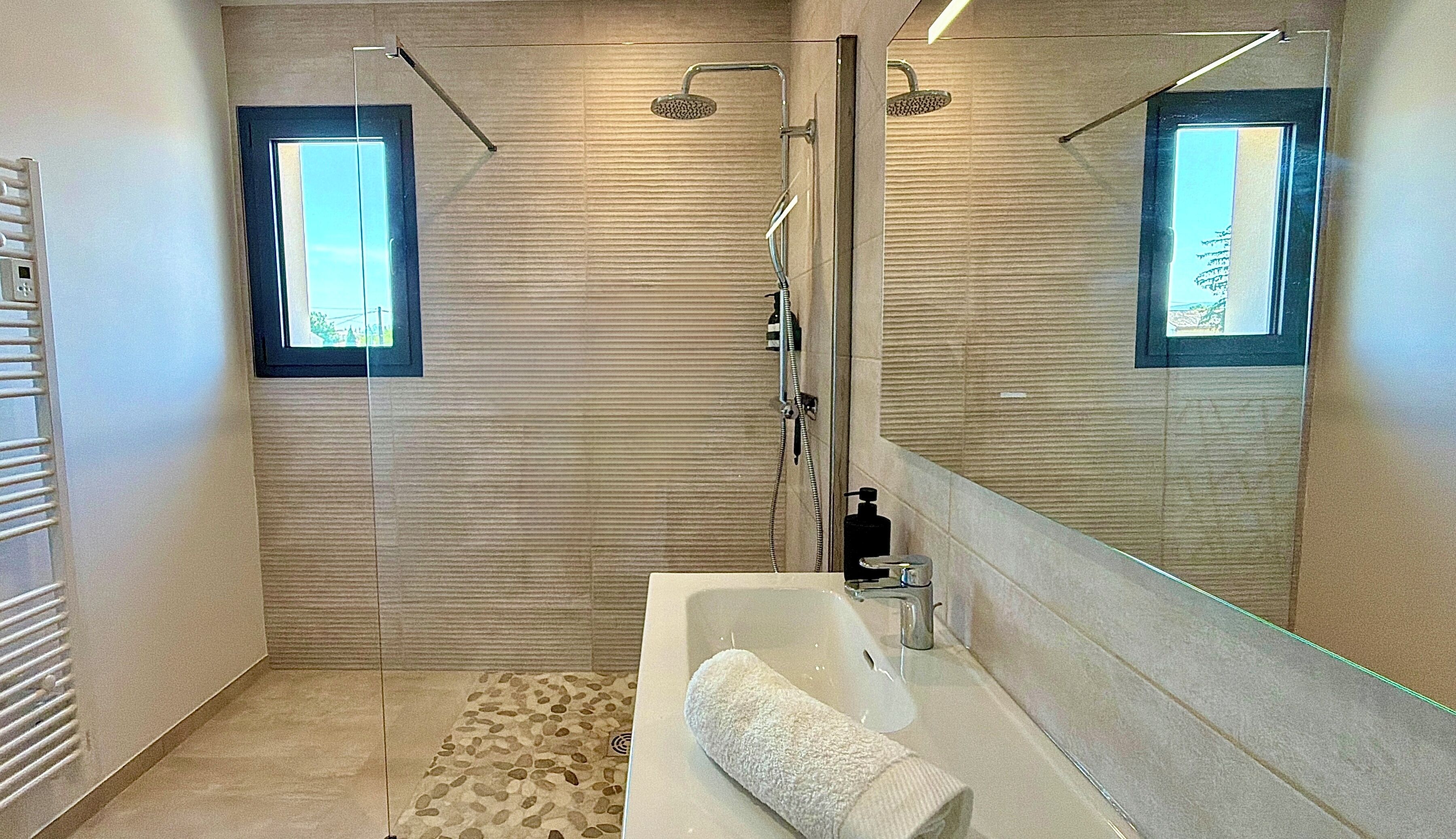 Een moderne badkamer met een douche, een badkuip, een grote spiegel en een raam.