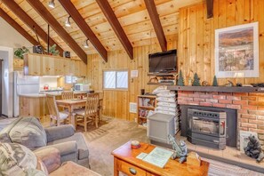 Ein Holzinnenraum mit Küche, Essbereich und Wohnbereich, ausgestattet mit einem Kamin und einem Fernseher.