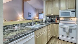 A kitchen with granite countertops, wooden cabinets, a white stove, and a microwave. - Updated condo w/ shared Pools, Hot Tubs, Saunas, Fitness Room & Tennis Courts (Mammoth Lakes)