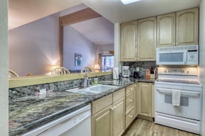 A kitchen with granite countertops, wooden cabinets, a white stove, and a microwave. - Updated condo w/ shared Pools, Hot Tubs, Saunas, Fitness Room & Tennis Courts (Mammoth Lakes)