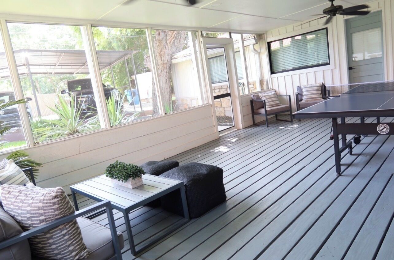 An outdoor patio with a table and chairs, a ceiling fan, and a view of the backyard.