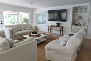 A modern living room with a sofa set, a coffee table, and a television mounted on the wall. - Docktails and Daydreams lake LBJ bungalow sleeps 13 (Burnet)