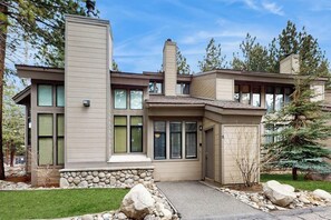 A modern two-story house with a stone foundation, large windows, and a stone pathway leading to the entrance. - Remodeled, luxury townhome w/ shared pool, hot tub, & complex game room (Mammoth Lakes)