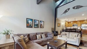 Un salon avec un canapé, une table basse et un divan blanc. Des tableaux encadrés ornent le mur.