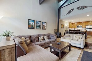 A living room with a sofa, a coffee table, and a white couch. There are framed pictures on the wall. - Remodeled, luxury townhome w/ shared pool, hot tub, & complex game room (Mammoth Lakes)