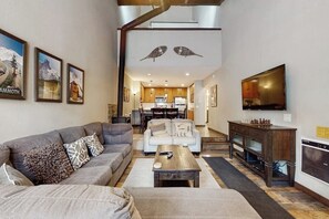 A living room with a sofa, coffee table, TV, and artwork on the walls. - Remodeled, luxury townhome w/ shared pool, hot tub, & complex game room (Mammoth Lakes)