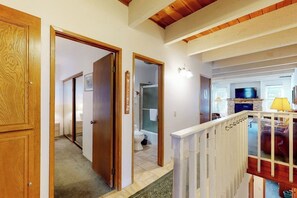 Ein Flur mit Holztüren, einer Treppe und einem Wohnbereich mit Fernseher und Sofa.