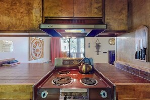 A kitchen with a vintage stove, wooden cabinets, and a window with a view. - Charming mountain condo w/ shared pool, hot tub, & easy slope access (Mammoth Lakes)