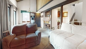 A bedroom with a bed, a sofa, a dining area, and a staircase. - Contemporary condo near The Village with easy slope access, balcony & hot tub (Mammoth Lakes)