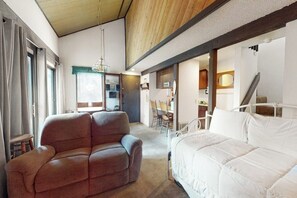 A bedroom with a bed, a sofa, a dining area, and a staircase. - Contemporary condo near The Village with easy slope access, balcony & hot tub (Mammoth Lakes)