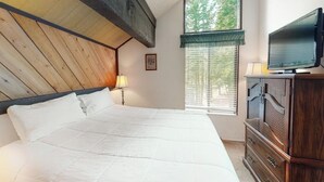 A bedroom with a wooden ceiling, a large bed with white bedding, a television on a wooden cabinet, and a window with blinds. - Contemporary condo near The Village with easy slope access, balcony & hot tub (Mammoth Lakes)