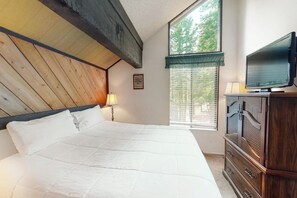 A bedroom with a wooden ceiling, a large bed with white bedding, a television on a wooden cabinet, and a window with blinds. - Contemporary condo near The Village with easy slope access, balcony & hot tub (Mammoth Lakes)