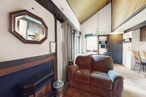 A living room with a fireplace, a large mirror, and a sofa. - Contemporary condo near The Village with easy slope access, balcony & hot tub (Mammoth Lakes)