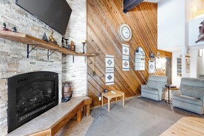Ein Wohnzimmer mit Kamin, Holzvertäfelung, einer Uhr und einem Sofa.
