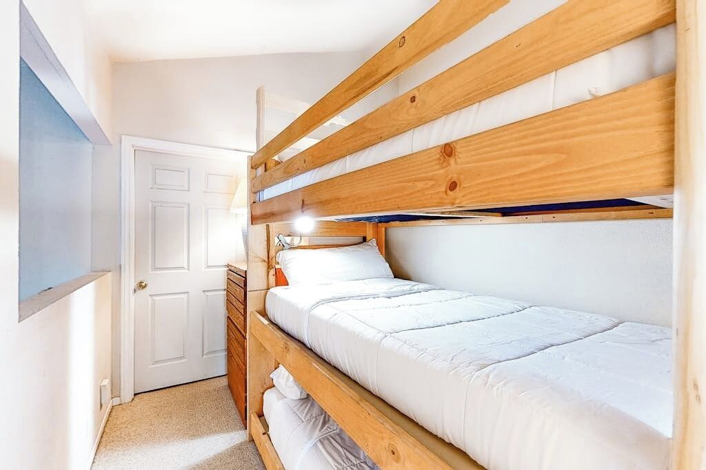 Ein Schlafraum mit Etagenbett, einer weißen Tür und einem kleinen Fenster.