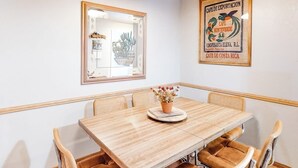 A dining area with a wooden table, cushioned chairs, and a potted plant.
