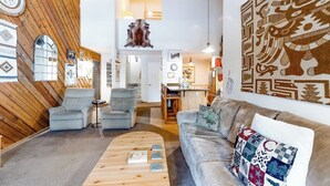 A modern living room with a wooden accent wall, a sofa, a coffee table, and a wall-mounted clock.