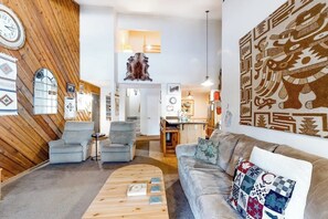 Ein modernes Wohnzimmer mit einer Wand in Holzoptik, einem Sofa, einem Couchtisch und einer Wanduhr.