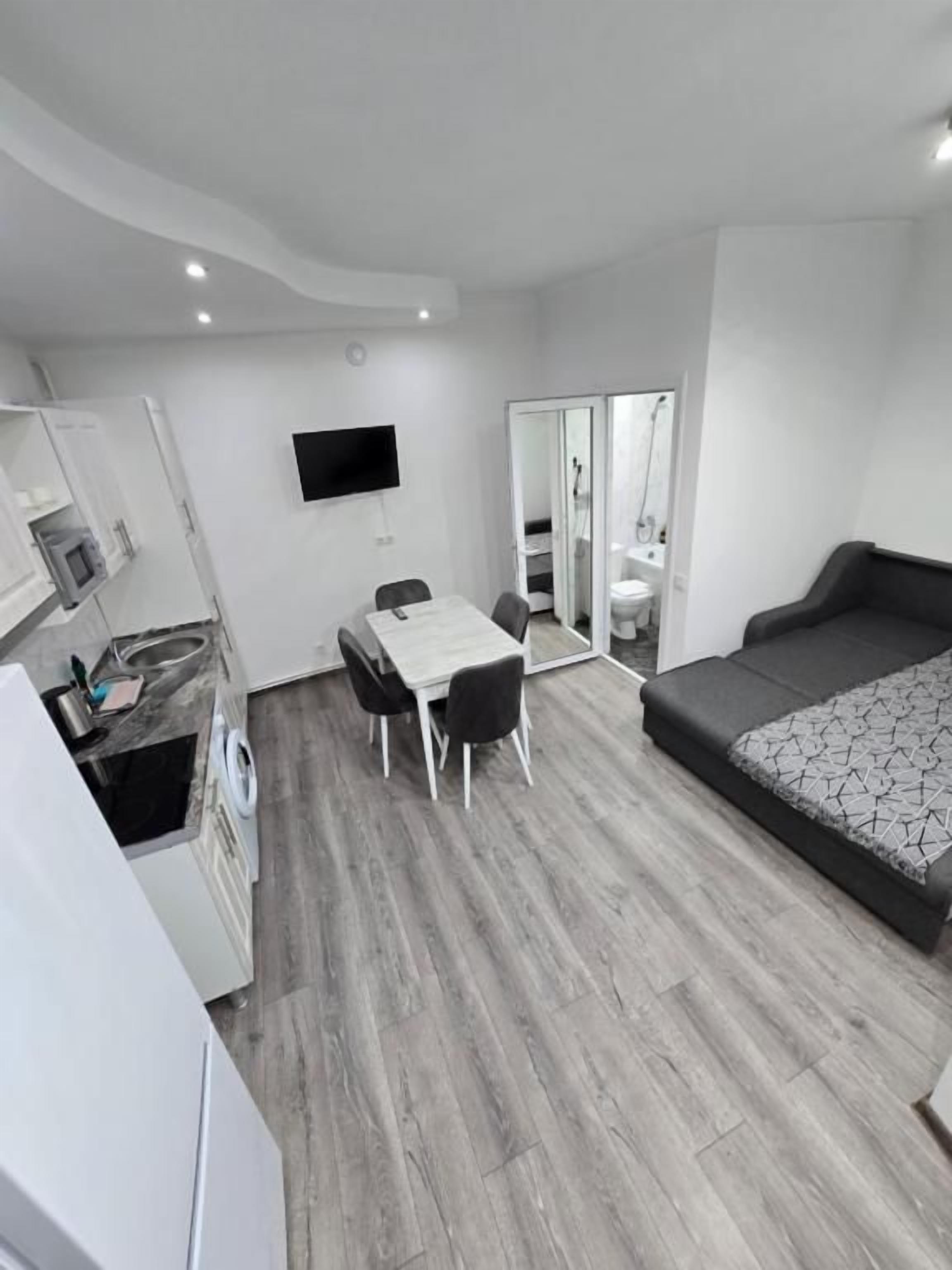 Una habitación de hotel moderna con televisión de pantalla plana, zona de comedor, sofá cama y vestidor.