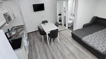 Une chambre d’hôtel moderne dotée d’une télévision à écran plat, d’un coin repas, d’un canapé-lit et d’un dressing.