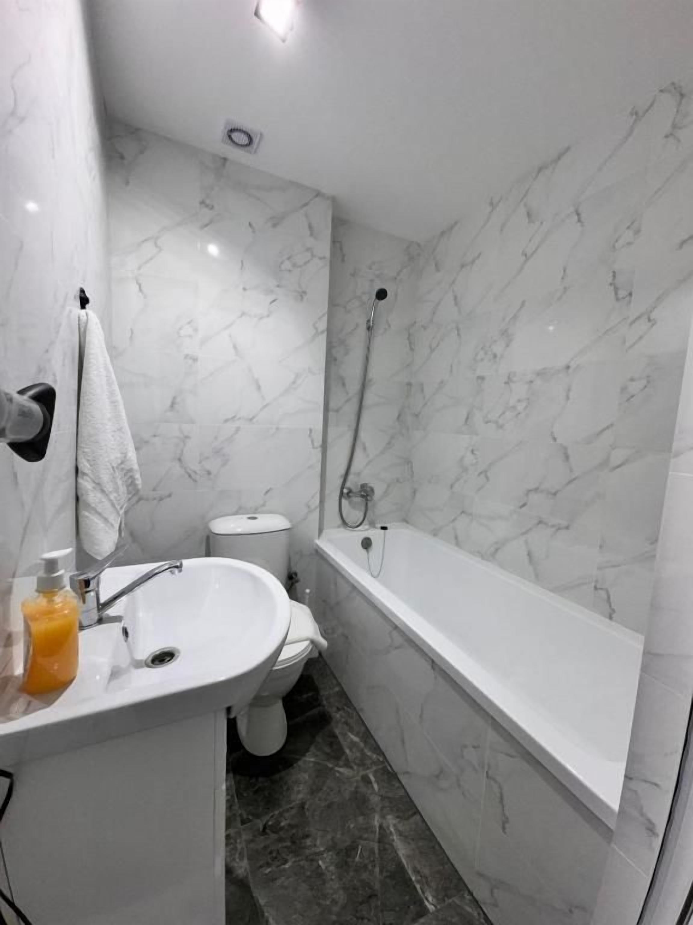 Un baño con lavamanos, inodoro y bañera blancos.