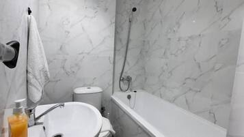 Un baño con lavamanos, inodoro y bañera blancos.