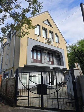 A two-story building with a balcony, a gated entrance, and a clear sky. - Small House ApartHotel (Chișinău)