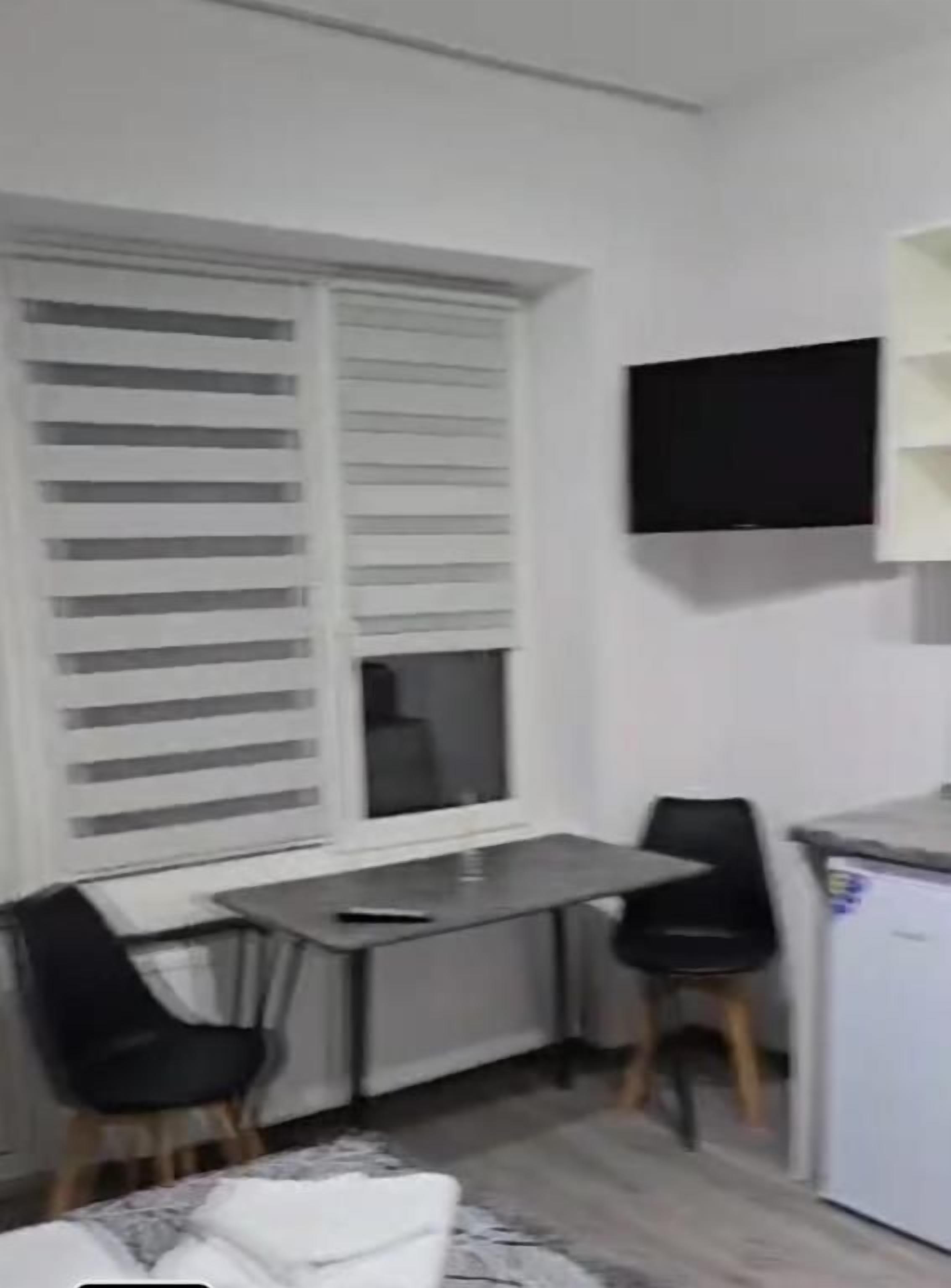 Une petite pièce comprenant un lit, un bureau, une chaise, un téléviseur et un réfrigérateur.