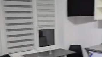 Une petite pièce comprenant un lit, un bureau, une chaise, un téléviseur et un réfrigérateur.
