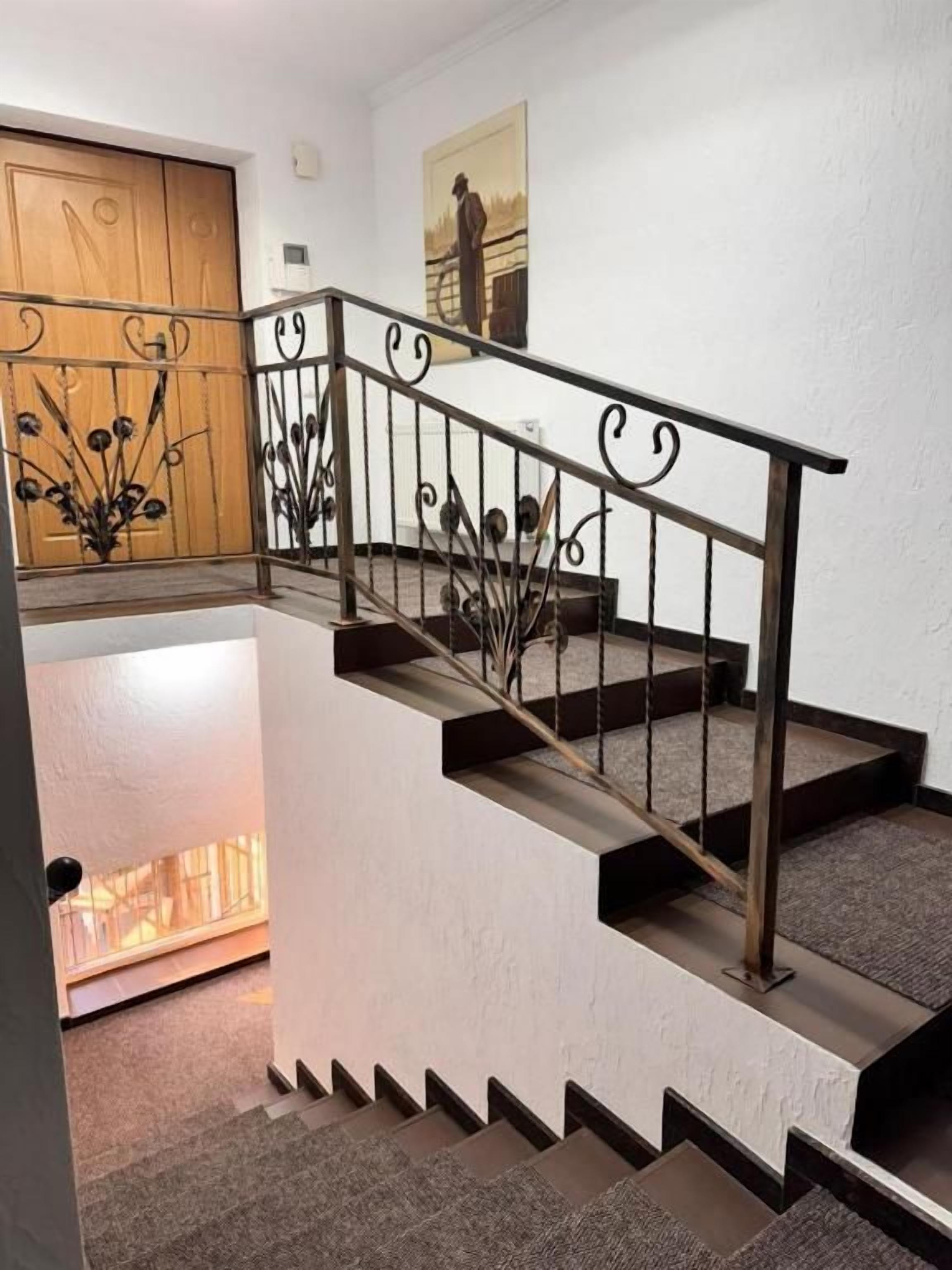 A staircase with a metal railing, wooden steps, and a door at the top.