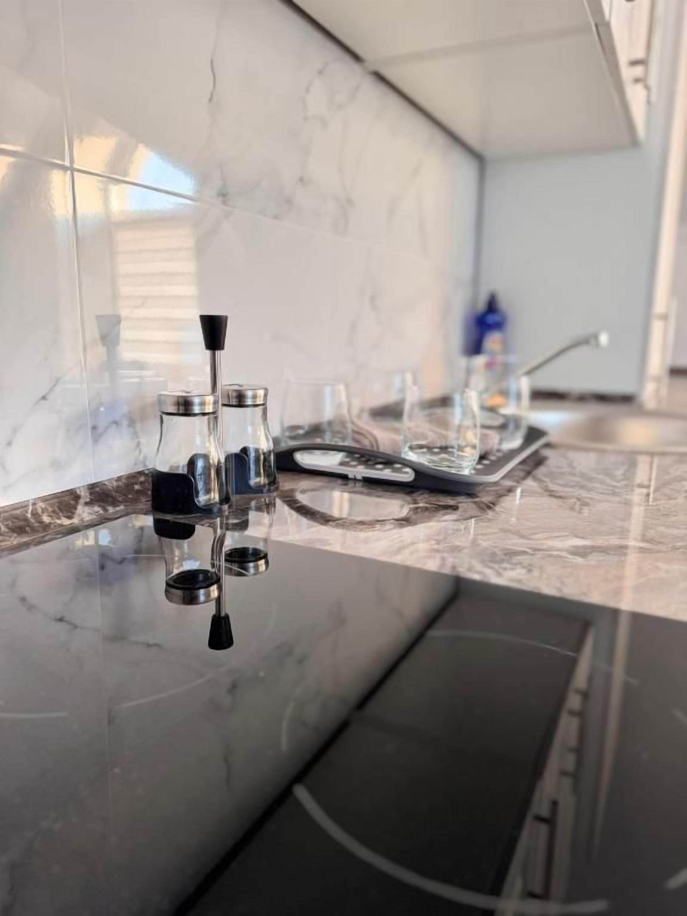 Una cocina con encimera de mármol, cafetera y lavabo.
