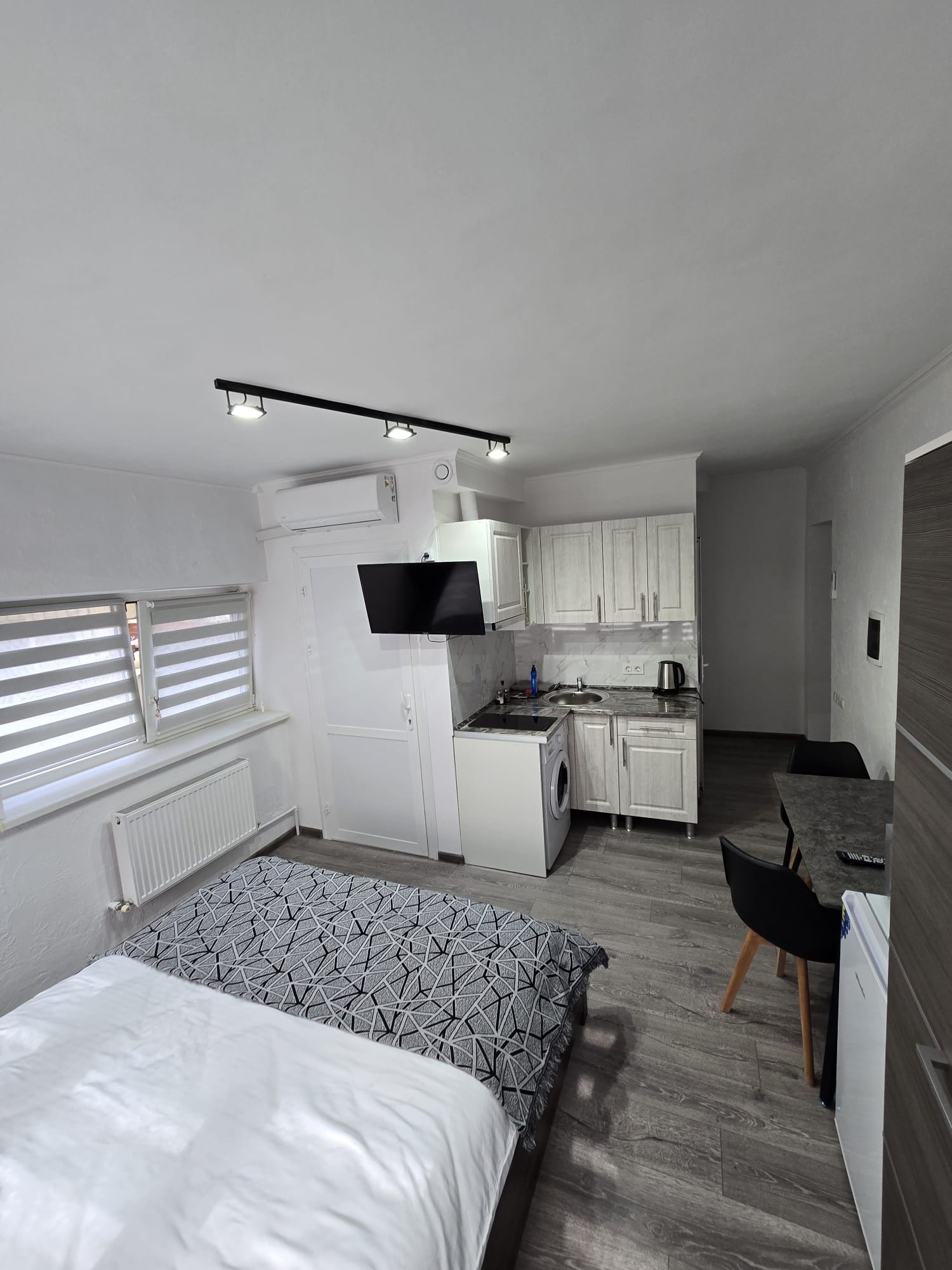 A compact room with a bed, a kitchenette, and a small dining area.
