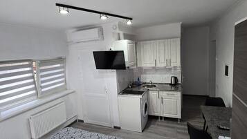 A compact room with a bed, a kitchenette, and a small dining area.