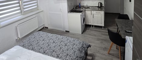 A compact room with a bed, a kitchenette, and a small dining area.
